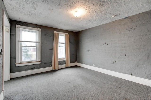 carpeted spare room with a textured ceiling and baseboards