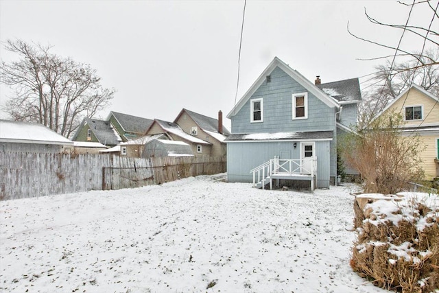 snow covered property with fence and a chimney