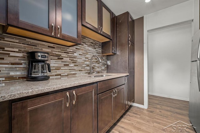 2119 Bayliss St, Midland, MI 48640 - kitchen featuring a sink, light wood finished floors, dark brown cabinetry, and decorative backsplash
