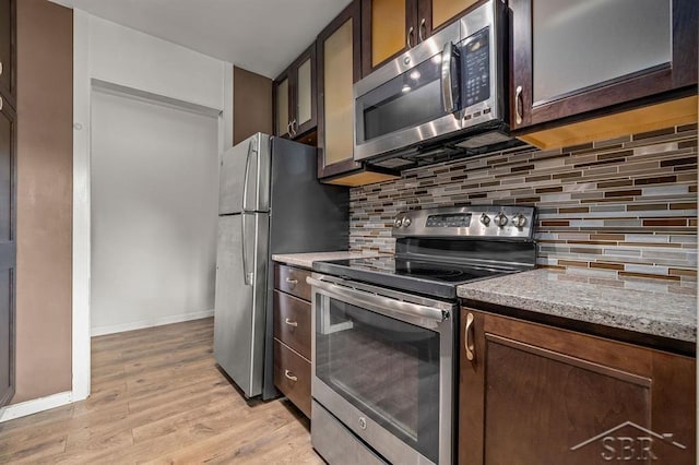 2119 Bayliss St, Midland, MI 48640 - kitchen featuring appliances with stainless steel finishes, light wood finished floors, baseboards, decorative backsplash, and light stone counters