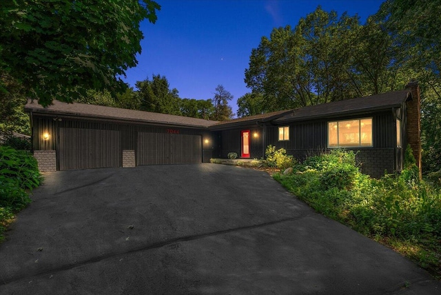7044 Cascade Rd SE, Grand Rapids, MI 49546 - view of front of house with an attached garage, asphalt driveway, brick siding, a chimney, and board and batten siding