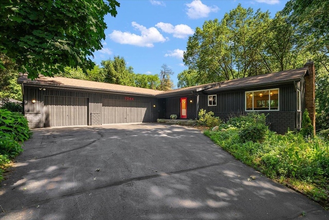 7044 Cascade Rd SE, Grand Rapids, MI 49546 - ranch-style house featuring an attached garage, asphalt driveway, a chimney, and board and batten siding