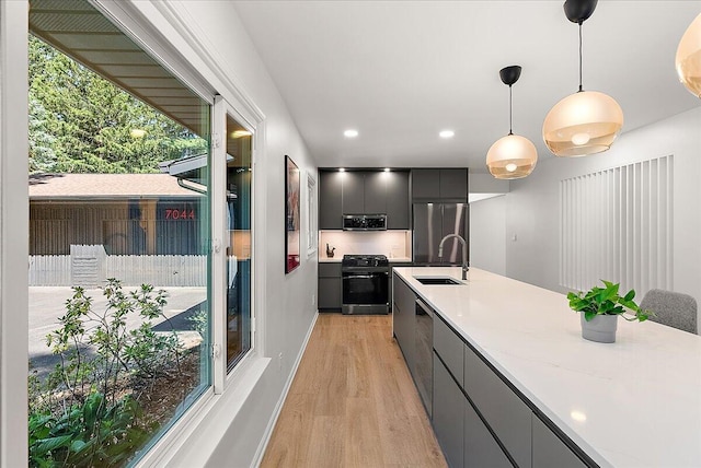 7044 Cascade Rd SE, Grand Rapids, MI 49546 - kitchen featuring appliances with stainless steel finishes, modern cabinets, light wood finished floors, decorative light fixtures, and light countertops