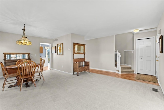 9009 N Pheasant Ridge Ln, Saline, MI 48176 - dining area with light colored carpet, stairway, baseboards, and a chandelier