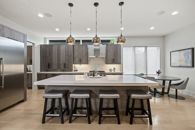 628 Watkins St, Birmingham, MI 48009 - kitchen with stainless steel built in fridge, wall chimney exhaust hood, a breakfast bar, light countertops, and recessed lighting