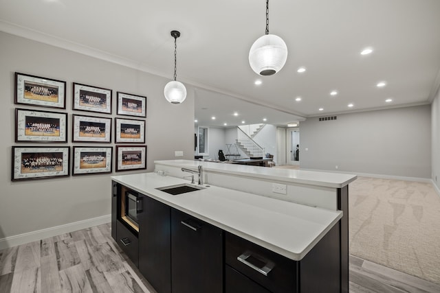 628 Watkins St, Birmingham, MI 48009 - kitchen featuring dark cabinetry, a sink, open floor plan, an island with sink, and light countertops