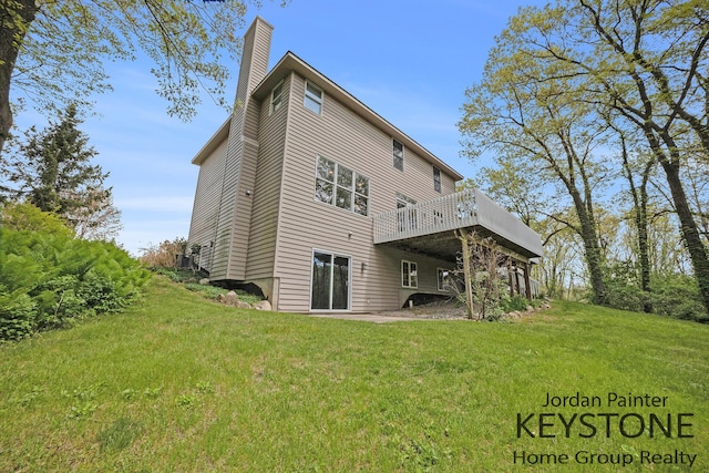 rear view of house with a deck, a yard, and a chimney
