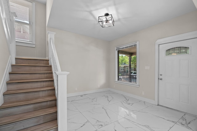 foyer featuring marble look tile flooring, stairs, and baseboards