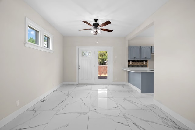 foyer entrance featuring baseboards, ceiling fan, and light marble finish flooring