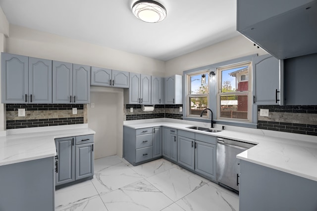 kitchen with gray cabinetry, a sink, stainless steel dishwasher, tasteful backsplash, and light stone counters