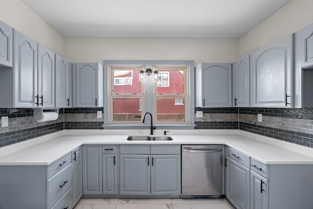 kitchen featuring dishwasher, a sink, gray cabinets, light marble finish floors, and backsplash