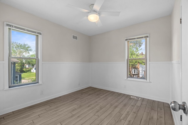 spare room with wainscoting, wood finished floors, and ceiling fan