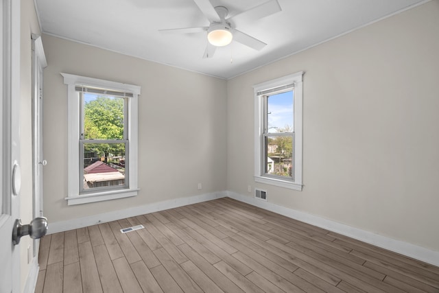 spare room featuring healthy amount of natural light, wood finished floors, baseboards, and crown molding