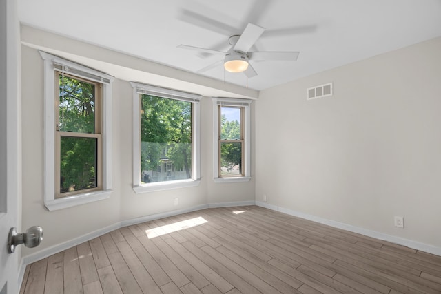 unfurnished room with plenty of natural light, wood finished floors, ceiling fan, and baseboards
