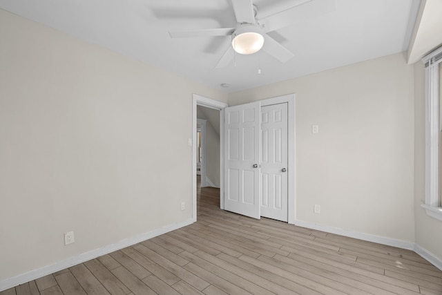 unfurnished bedroom featuring wood finished floors, baseboards, a closet, and a ceiling fan