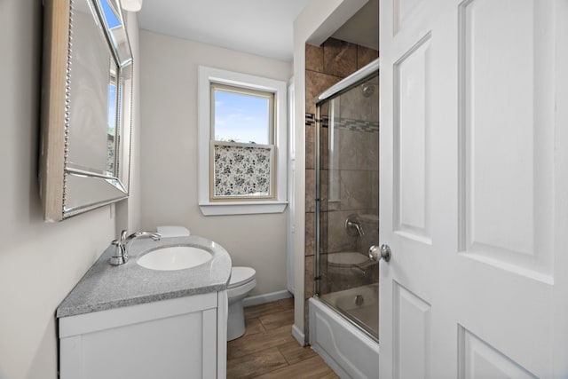 full bathroom featuring toilet, baseboards, vanity, combined bath / shower with glass door, and wood finished floors