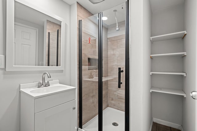 full bath with a shower stall, vanity, tile patterned flooring, and baseboards