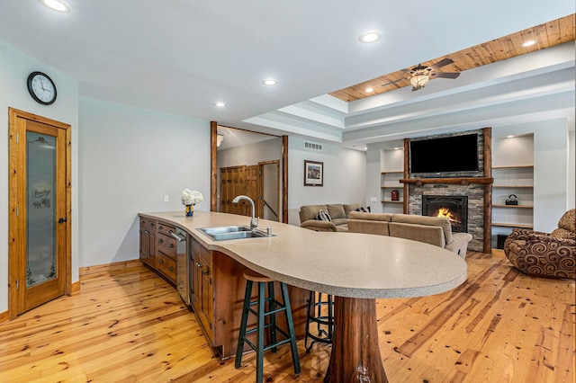 4435 Imlay City Rd, Attica, MI 48412 - kitchen featuring a sink, light wood finished floors, a peninsula, a stone fireplace, and a kitchen breakfast bar