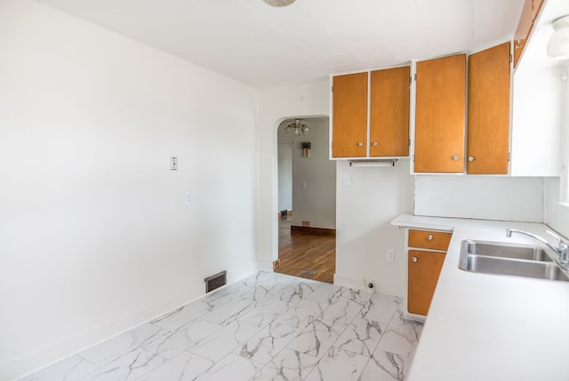 kitchen with brown cabinets, a sink, light countertops, and baseboards