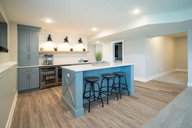 3280 Amtrak Dr SW, Byron Center, MI 49315 - kitchen featuring wine cooler, light wood-style floors, baseboards, a breakfast bar area, and open shelves