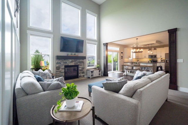3280 Amtrak Dr SW, Byron Center, MI 49315 - living area with a chandelier, light carpet, a fireplace, a towering ceiling, and baseboards