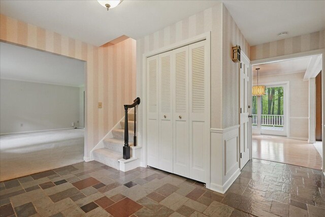 1558 Sylvan Glen Rd, Okemos, MI 48864 - corridor with wallpapered walls, stone tile flooring, stairway, and baseboards