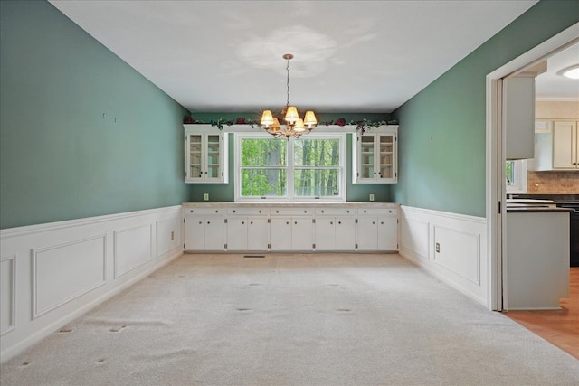 1558 Sylvan Glen Rd, Okemos, MI 48864 - unfurnished dining area featuring a chandelier, a decorative wall, a wainscoted wall, and light carpet