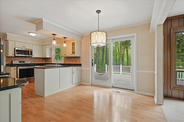1558 Sylvan Glen Rd, Okemos, MI 48864 - kitchen with appliances with stainless steel finishes, dark countertops, ornamental molding, baseboards, and light wood-style floors