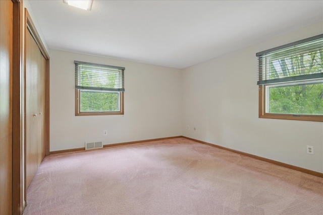 1558 Sylvan Glen Rd, Okemos, MI 48864 - unfurnished bedroom with multiple windows, light colored carpet, and baseboards