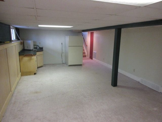 110 N 1st St, Holly, MI 48442 - finished below grade area featuring freestanding refrigerator, stairs, and a paneled ceiling