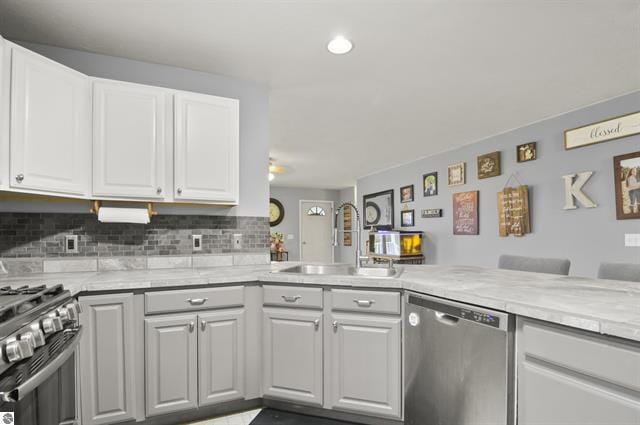 2426 E 48 1/2 Rd, Cadillac, MI 49601 - kitchen featuring stainless steel appliances, a sink, light countertops, backsplash, and white cabinets