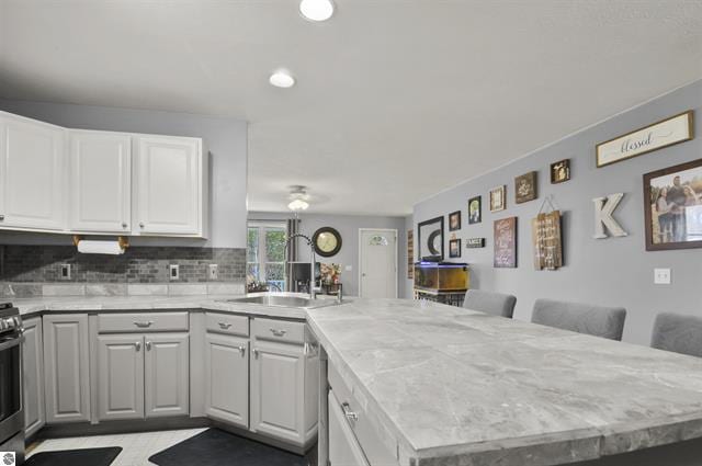 2426 E 48 1/2 Rd, Cadillac, MI 49601 - kitchen with a peninsula, light countertops, a sink, tasteful backsplash, and ceiling fan