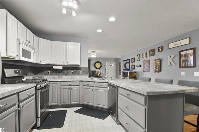 2426 E 48 1/2 Rd, Cadillac, MI 49601 - kitchen with stainless steel appliances, a peninsula, gray cabinets, a sink, and recessed lighting