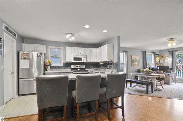2426 E 48 1/2 Rd, Cadillac, MI 49601 - kitchen with appliances with stainless steel finishes, white cabinets, light wood finished floors, decorative backsplash, and recessed lighting