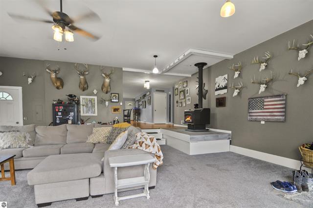 2426 E 48 1/2 Rd, Cadillac, MI 49601 - living area featuring a wood stove, a ceiling fan, and carpet flooring