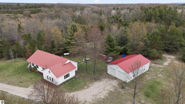 2426 E 48 1/2 Rd, Cadillac, MI 49601 - aerial view of property and surrounding area featuring a heavily wooded area