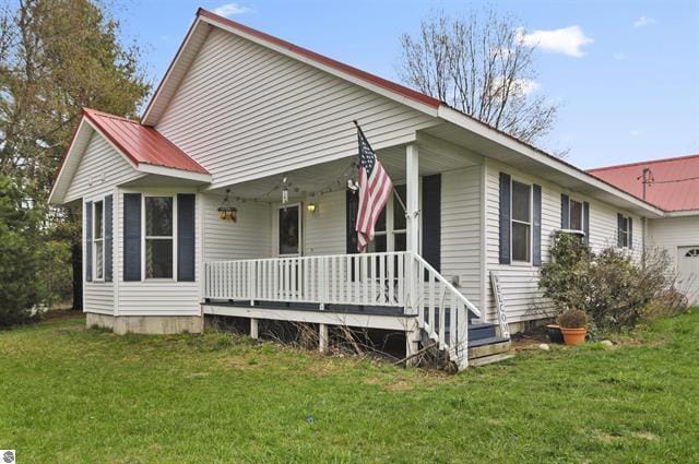 2426 E 48 1/2 Rd, Cadillac, MI 49601 - view of front facade featuring covered porch, a front lawn, and a garage