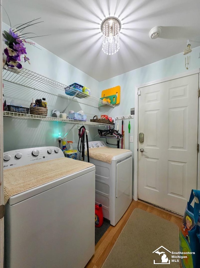 17795 Bobwhite Ct, Brownstown, MI 48192 - washroom featuring washer and dryer, light wood-style flooring, and a chandelier