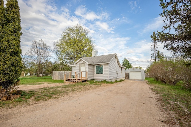 505 S Cherry St, Kalkaska, MI 49646 - view of front facade featuring dirt driveway, an outdoor structure, a detached garage, and a chimney