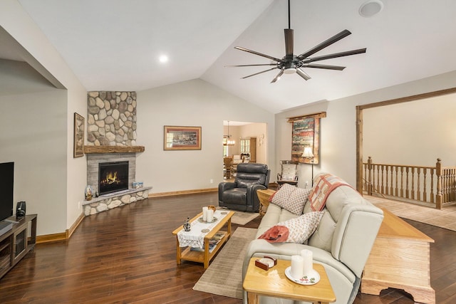 living room with ceiling fan, lofted ceiling, wood finished floors, a stone fireplace, and baseboards