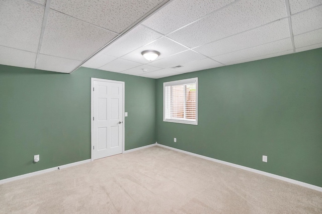 carpeted empty room with a drop ceiling and baseboards