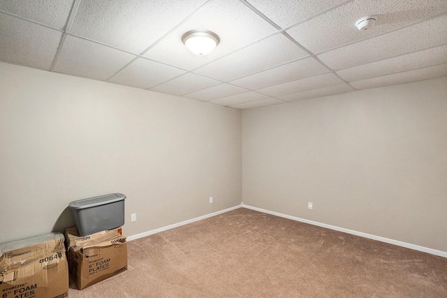 spare room featuring a drop ceiling, carpet, and baseboards