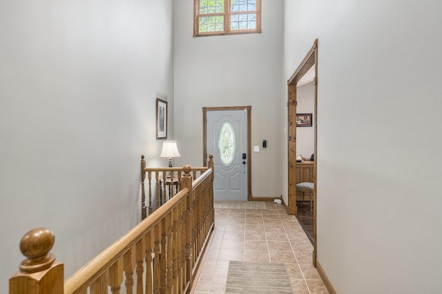 foyer featuring plenty of natural light, a towering ceiling, light tile patterned floors, and baseboards