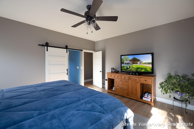 12640 Bucs Dr, Grand Haven, MI 49417 - bedroom with light wood-style flooring, a barn door, baseboards, and a ceiling fan