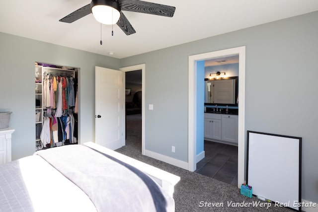 12640 Bucs Dr, Grand Haven, MI 49417 - bedroom with dark colored carpet, connected bathroom, baseboards, a closet, and a walk in closet