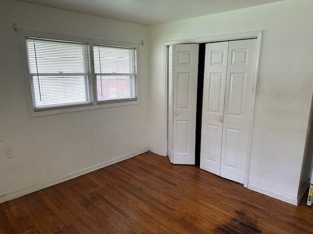 21383 Mada Ave, Southfield, MI 48075 - unfurnished bedroom with a closet, dark wood-style flooring, and baseboards