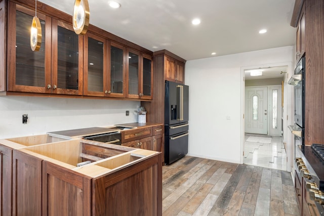 14240 Rosemont Ave, Detroit, MI 48223 - kitchen with black fridge, glass insert cabinets, wood finished floors, brown cabinetry, and recessed lighting