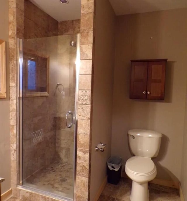 bathroom featuring a shower stall, toilet, and baseboards