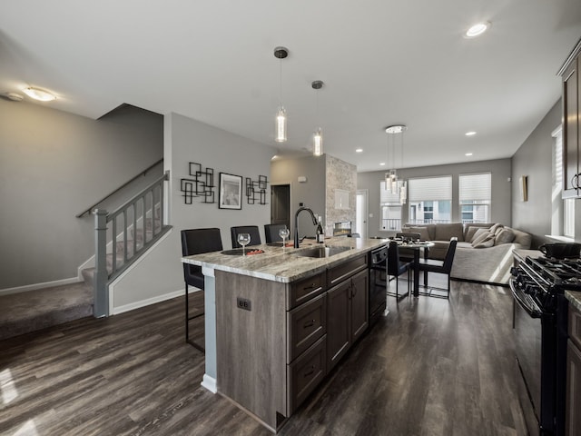 kitchen featuring a sink, black appliances, open floor plan, a kitchen bar, and dark wood-type flooring