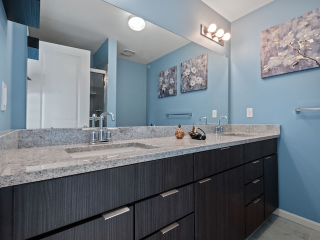 bathroom with a shower stall, double vanity, marble finish flooring, and baseboards